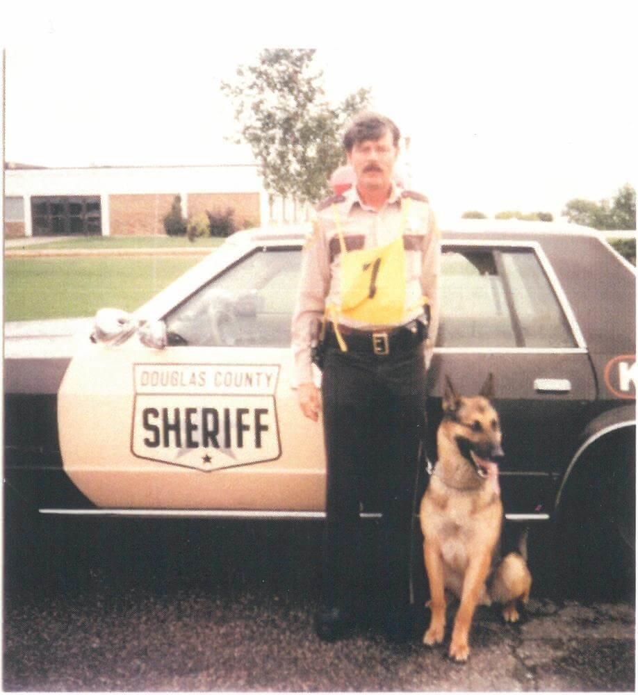 K-9 and partner standing next to their patrol car