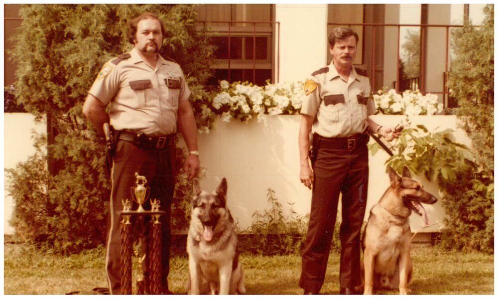 Two officers stand next to their K-9s