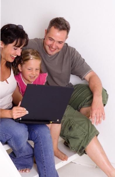 2 adults and 1 child sitting in front of a laptop